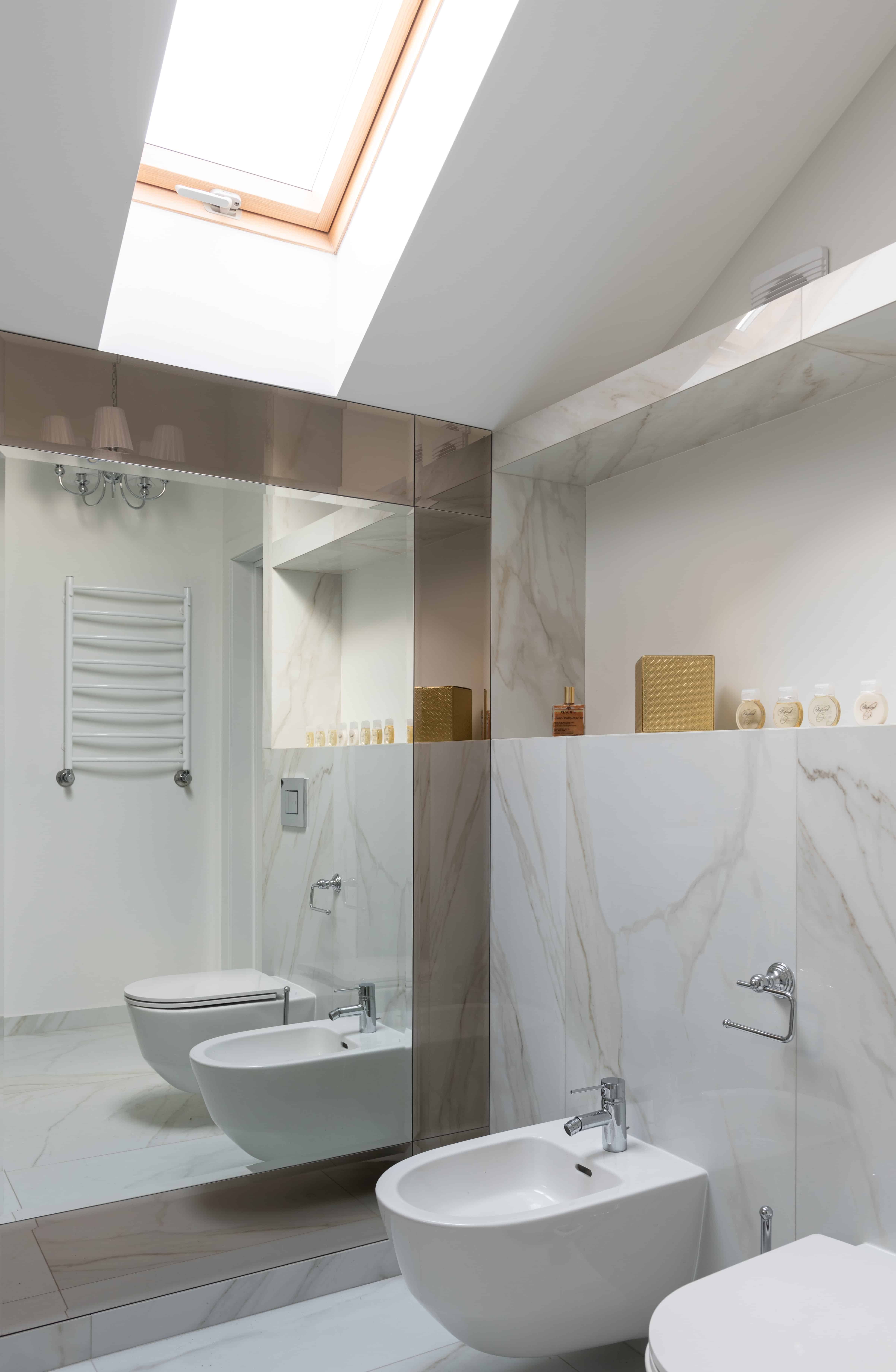 Toilet paper alternative: A white bidet fixture next to a toilet in a white marble bathroom.