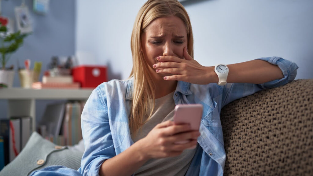 How to Get Through Hard Times upset woman on the couch holding cellphone